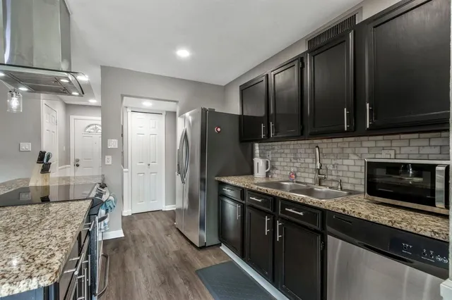 a kitchen with stainless steel appliances granite countertop a refrigerator a stove and a microwave oven with wooden floor