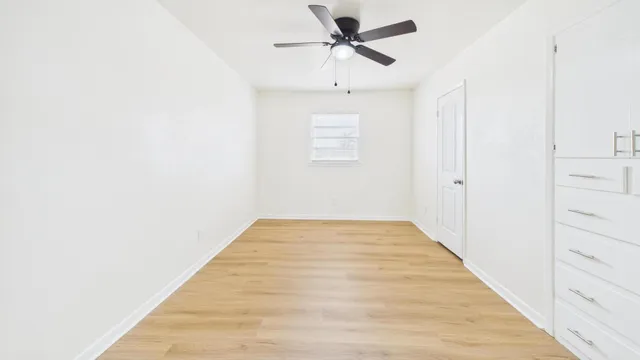 a view of a room with wooden floor and ceiling fan