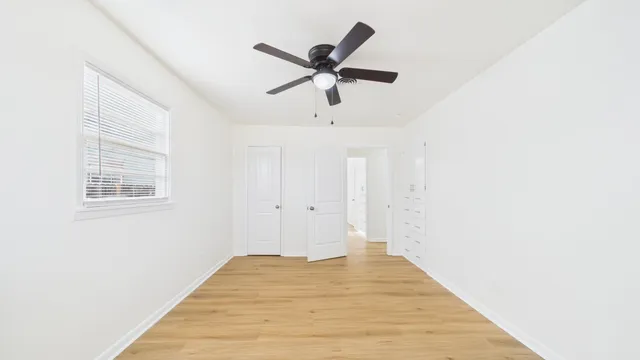 a view of empty room with wooden floor and ceiling fan