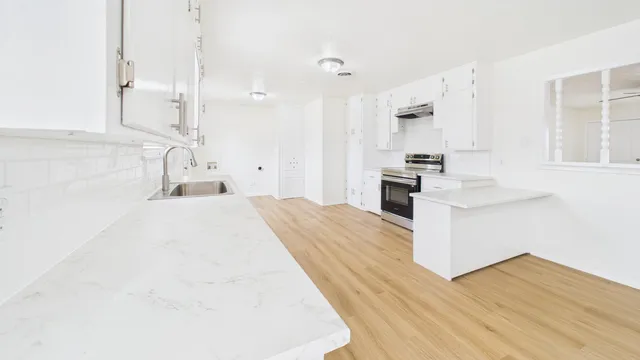 a large white kitchen with kitchen island a sink a stove and a refrigerator