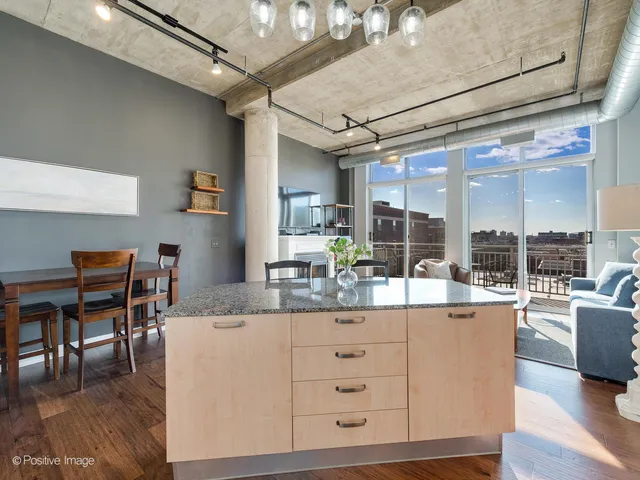 a dining hall with stainless steel appliances kitchen island granite countertop a table chairs and a couch