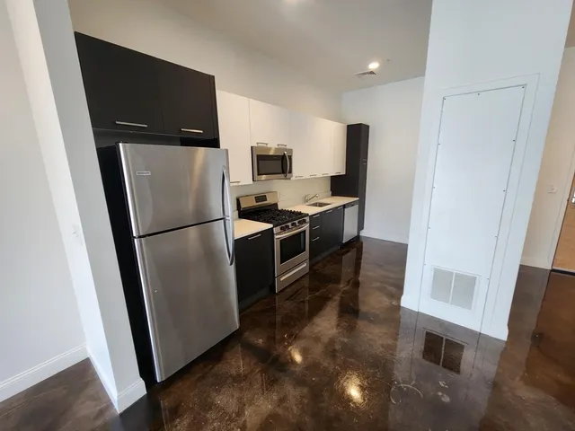 a view of a refrigerator in kitchen and an empty room