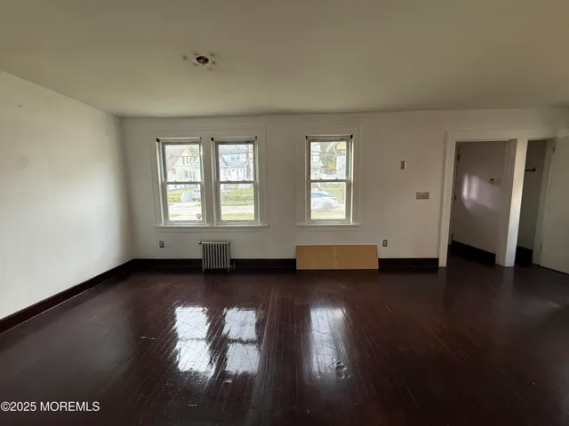 a view of empty room with wooden floor and windows