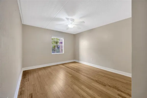 an empty room with wooden floor and ceiling fan
