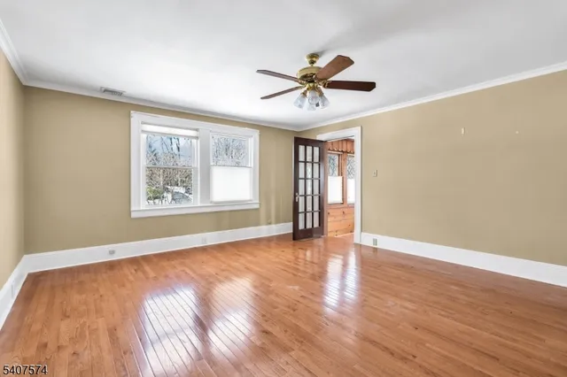 a view of an empty room with window and wooden floor