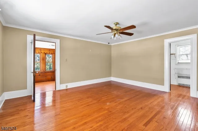 an empty room with wooden floor chandelier fan and windows