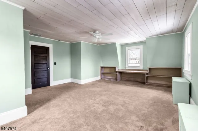 an empty room with windows and ceiling fan