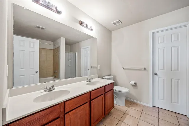 a bathroom with a double vanity sink toilet and a mirror