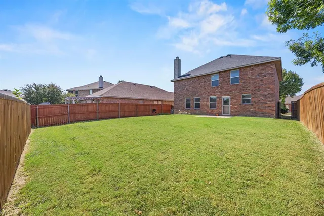 a view of a yard in front of a house with a large tree