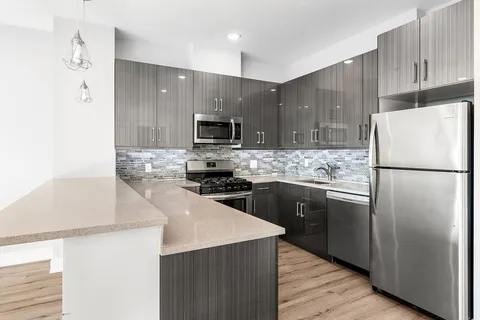 a kitchen with a refrigerator a microwave a sink and cabinets