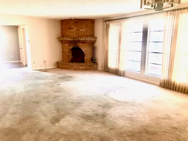 an empty room with a fireplace and windows