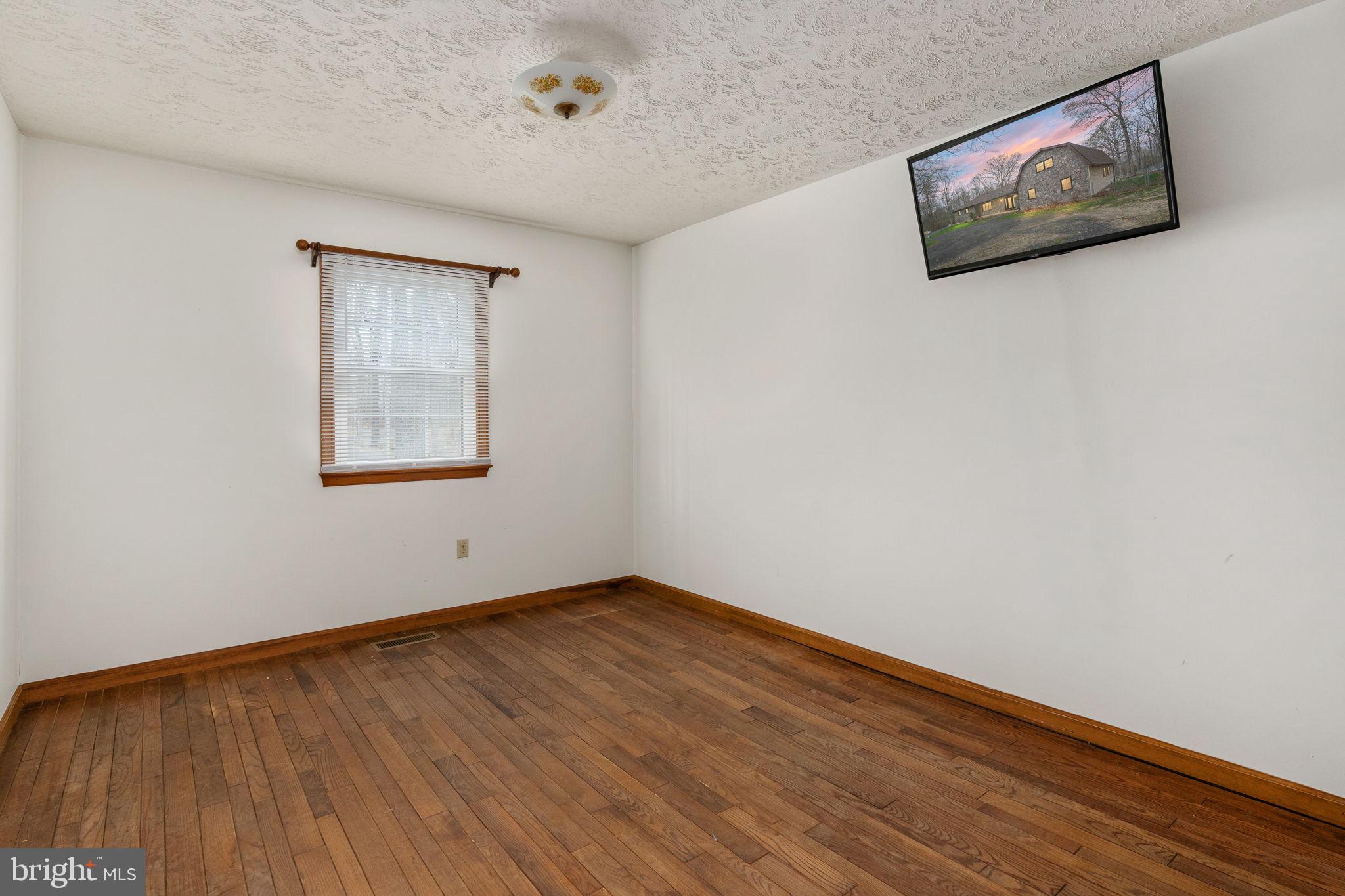 13220 Sillamon Road Goldvein, VA 22720 - Photo 8 of 57 a view of an empty room with wooden floor and a window