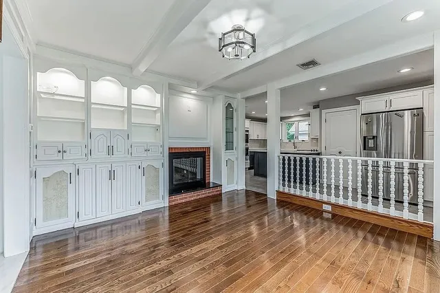 an empty room with wooden floor fireplace and windows