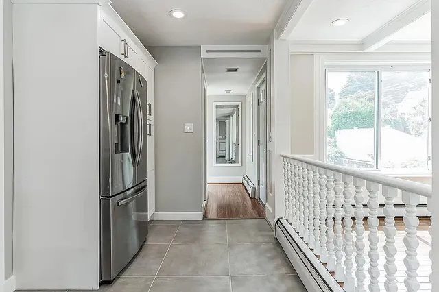 a view of a hallway with wooden floor and a bathroom