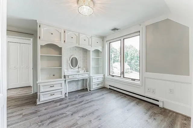 an empty room with wooden floor cabinet and windows
