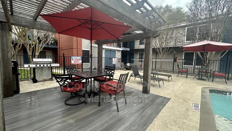 5426 Menchaca Road, Unit 214 Austin, TX 78745 - Photo 3 of 8 a view of a patio with a table and chairs under an umbrella