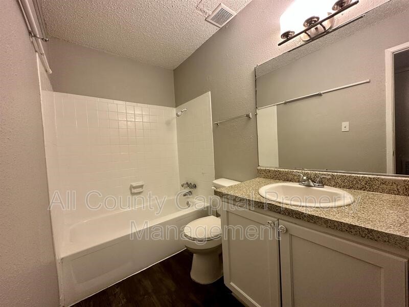 5426 Menchaca Road, Unit 214 Austin, TX 78745 - Photo 8 of 8 a bathroom with a granite countertop sink toilet a mirror and shower