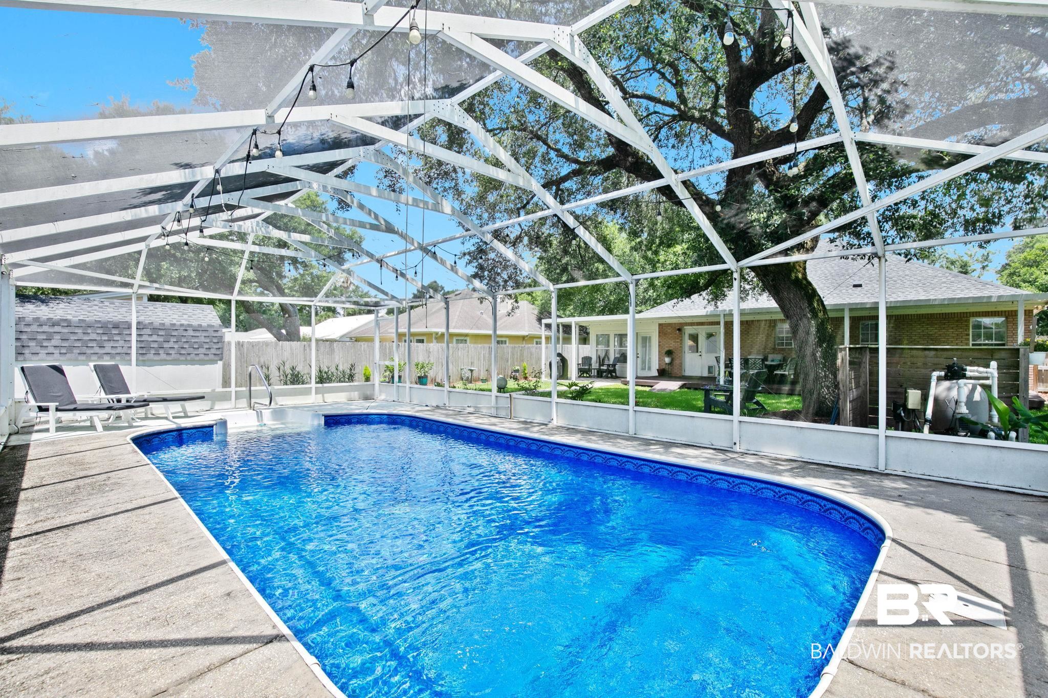 520 Juniper Place Drive Foley, AL 36535 - Photo 3 of 35 Screened swimming pool with a concrete deck, built-in steps, and a blue liner.