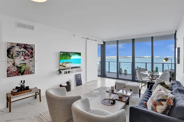 a living room with furniture floor to ceiling window and a flat screen tv