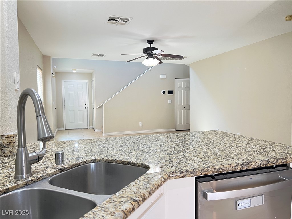 8708 Palomino Ranch Street Las Vegas, NV 89131 - Photo 3 of 19 Kitchen with stainless steel dishwasher, light stone counters, white cabinetry, and ceiling fan