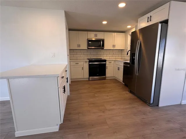 a kitchen with granite countertop a refrigerator and a stove top oven