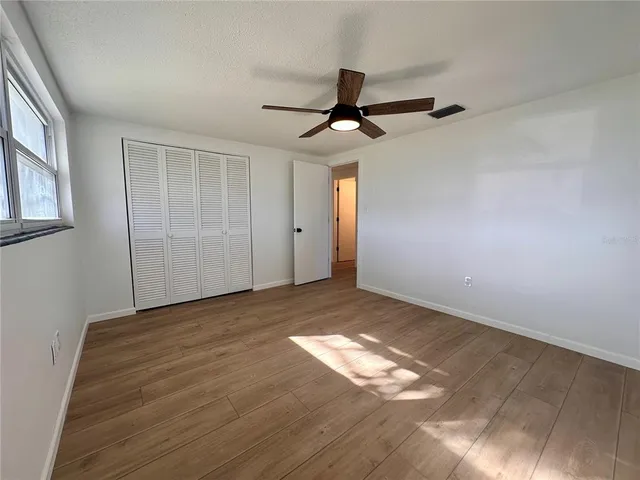 a view of empty room with wooden floor and fan