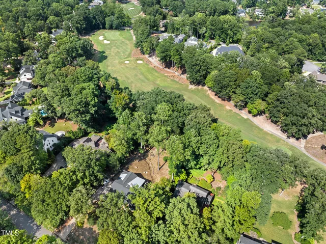 an aerial view of residential houses with outdoor space and trees all around
