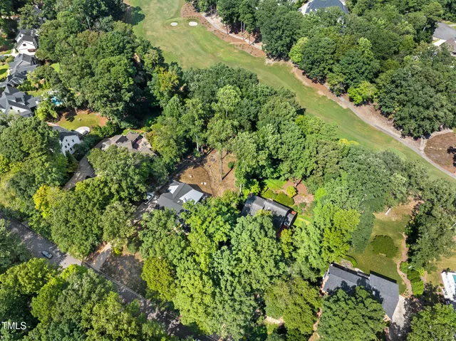 an aerial view of residential houses with outdoor space and trees all around