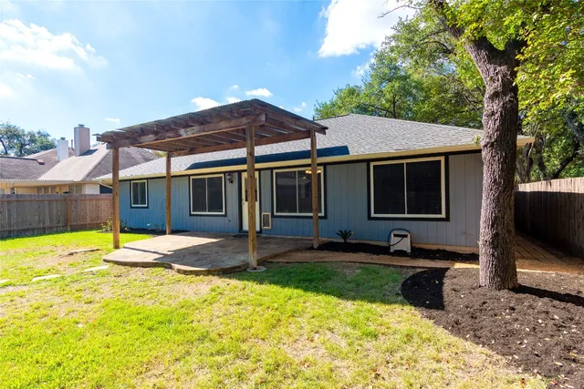 a view of a backyard with wooden fence and a large tree