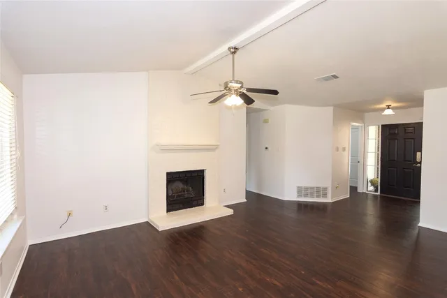 a view of a livingroom with wooden floor and a fireplace