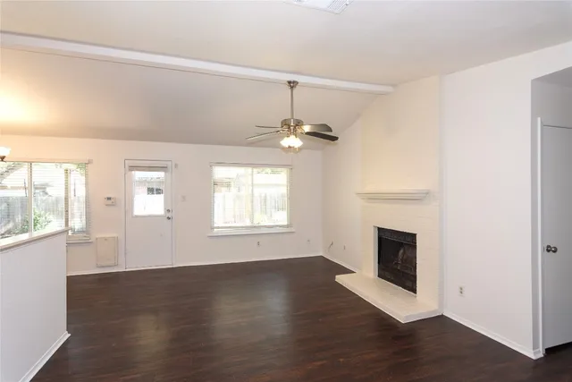 an empty room with wooden floor fireplace and windows