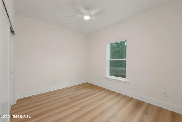 a view of an empty room with wooden floor and a window