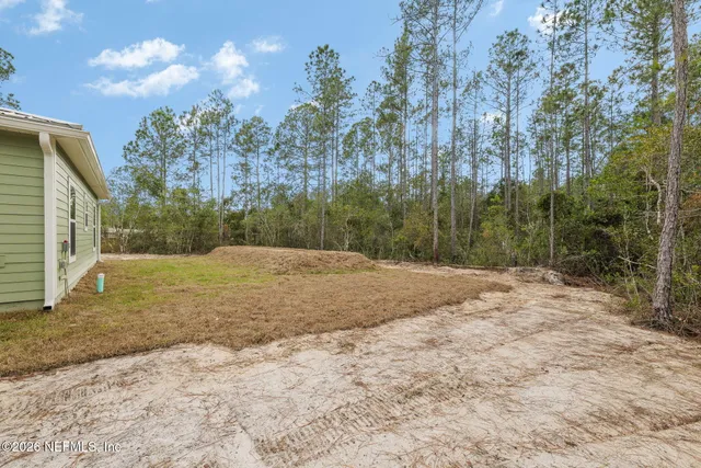 a view of house with backyard and trees in the background