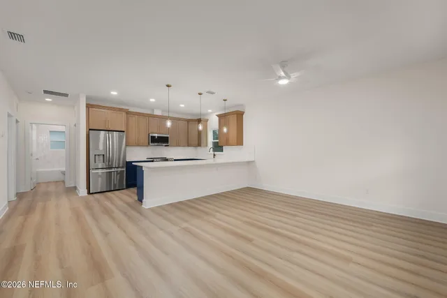 a kitchen with stainless steel appliances kitchen island granite countertop a refrigerator a sink and wooden floor