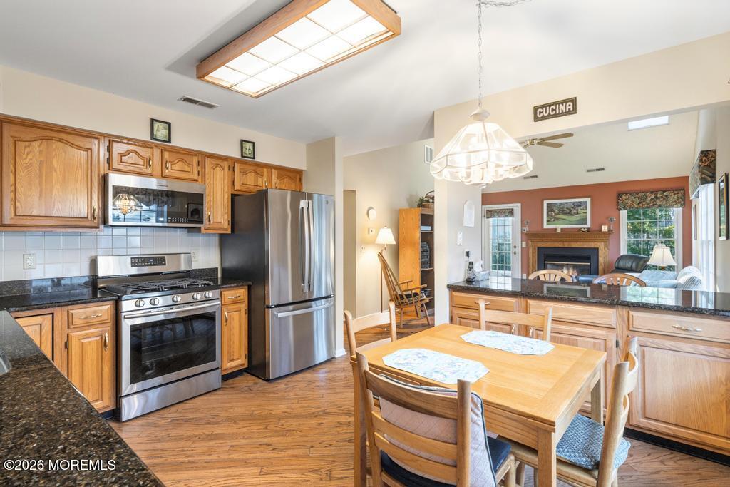 2287 Coral Leaf Road Toms River, NJ 08755 - Photo 12 of 38 a kitchen with stainless steel appliances granite countertop a kitchen island hardwood floor sink stove dining table and chairs