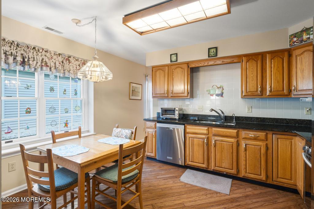 2287 Coral Leaf Road Toms River, NJ 08755 - Photo 14 of 38 a kitchen with granite countertop a sink dishwasher a dining table and chairs with wooden floor
