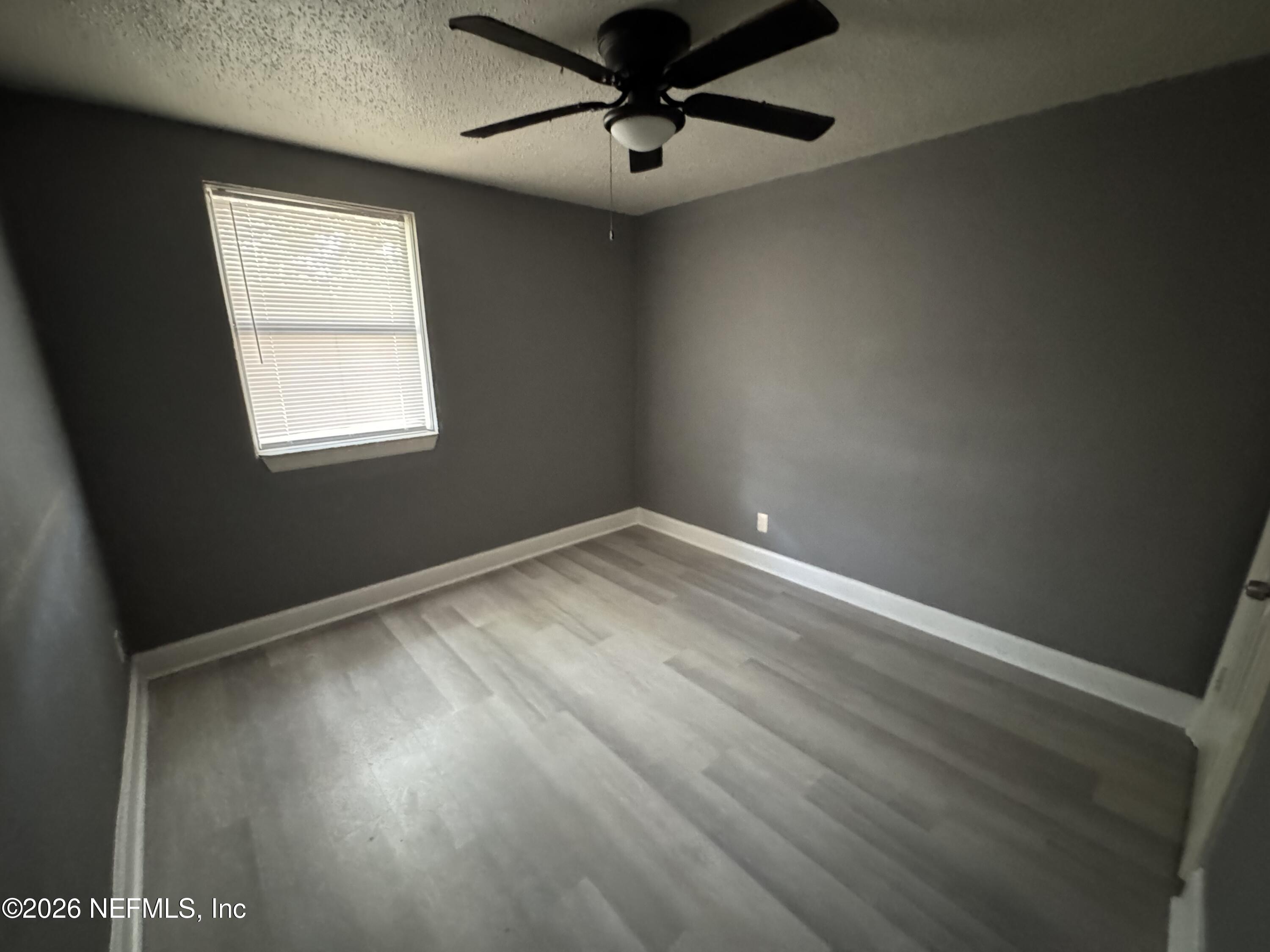 4114 Moncrief Road Jacksonville, FL 32209 - Photo 40 of 42 an empty room with wooden floor ceiling fan and windows
