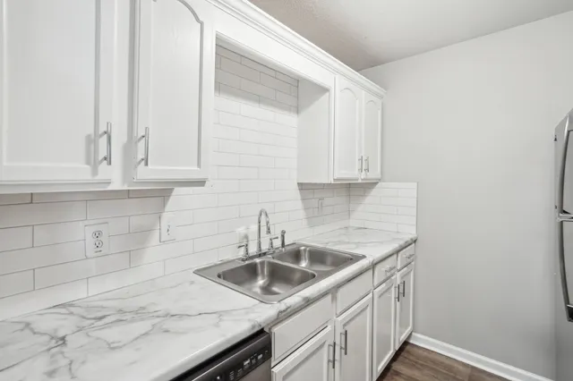 a kitchen with white cabinets a sink and dishwasher