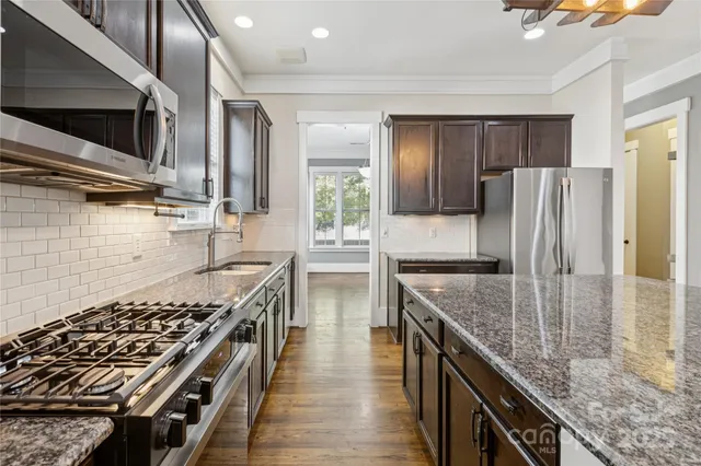 a kitchen with granite countertop a sink a stove and cabinets
