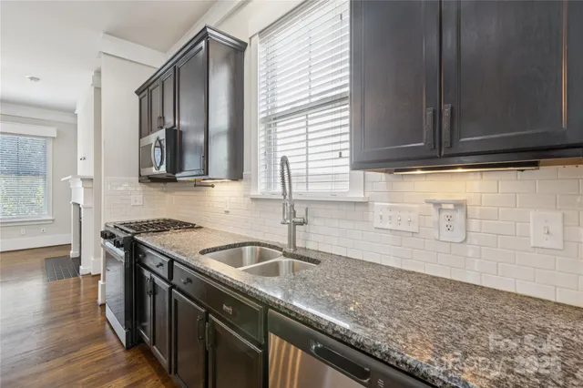 a kitchen with stainless steel appliances granite countertop a sink a refrigerator and wooden cabinets