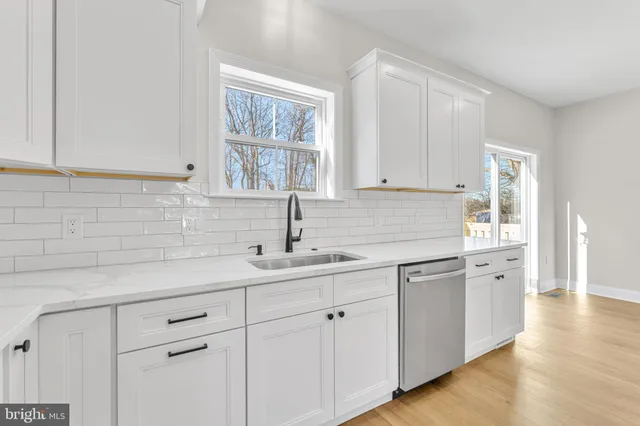 a kitchen with white cabinets white appliances and sink