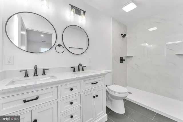 a bathroom with a granite countertop toilet a sink and a mirror