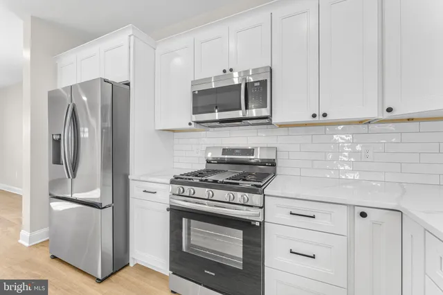 a kitchen with stainless steel appliances white cabinets and a stove a refrigerator with wooden floors