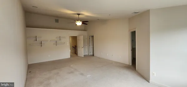 an empty room with closet and a chandelier fan