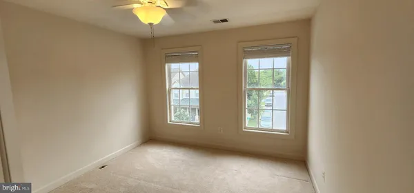 an empty room with windows and chandelier fan