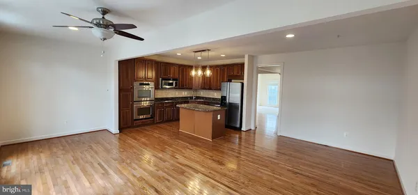a view of kitchen with stainless steel appliances wooden floor and a stove top oven