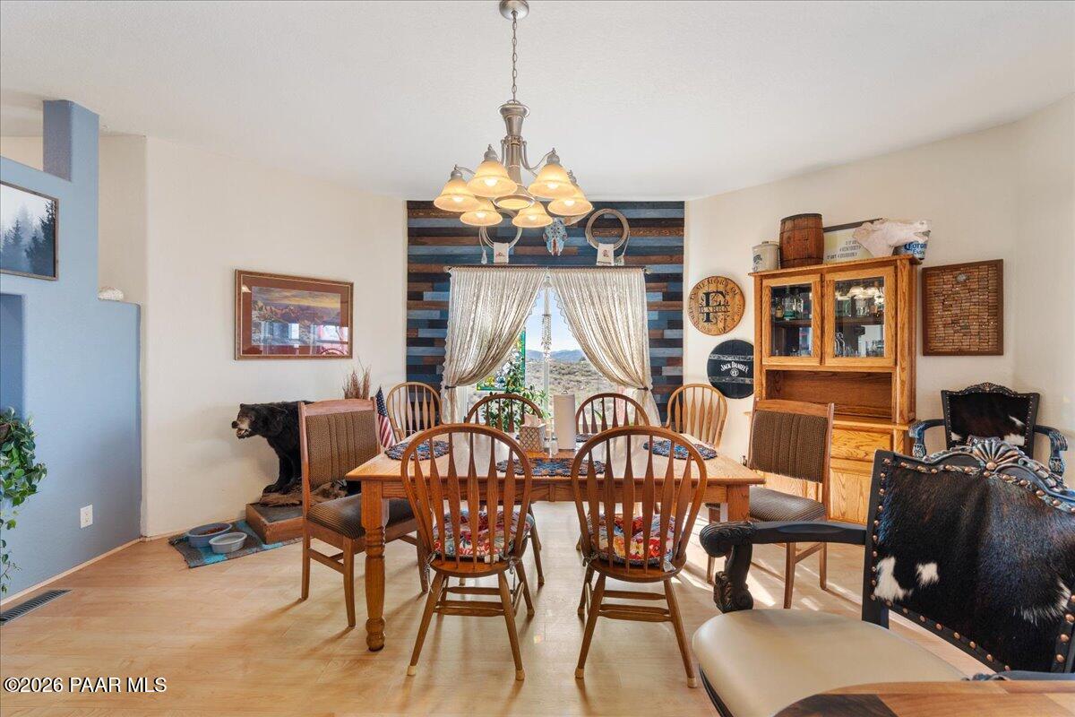 8475 West Red Rock Road Kirkland, AZ 86332 - Photo 15 of 39 a view of a dining room with furniture a chandelier and wooden floor