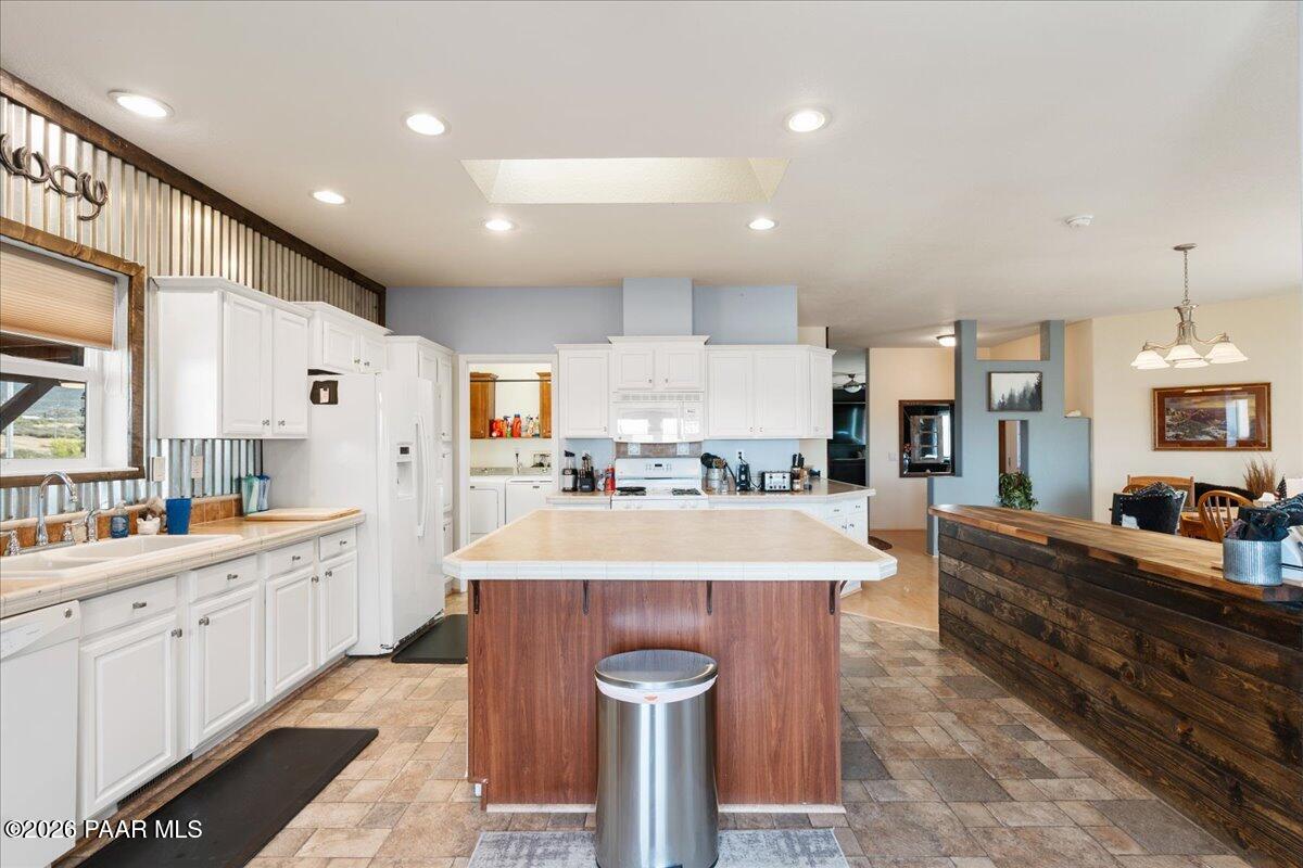 8475 West Red Rock Road Kirkland, AZ 86332 - Photo 20 of 39 a large kitchen with kitchen island a stove a sink a refrigerator and white cabinets with wooden floor