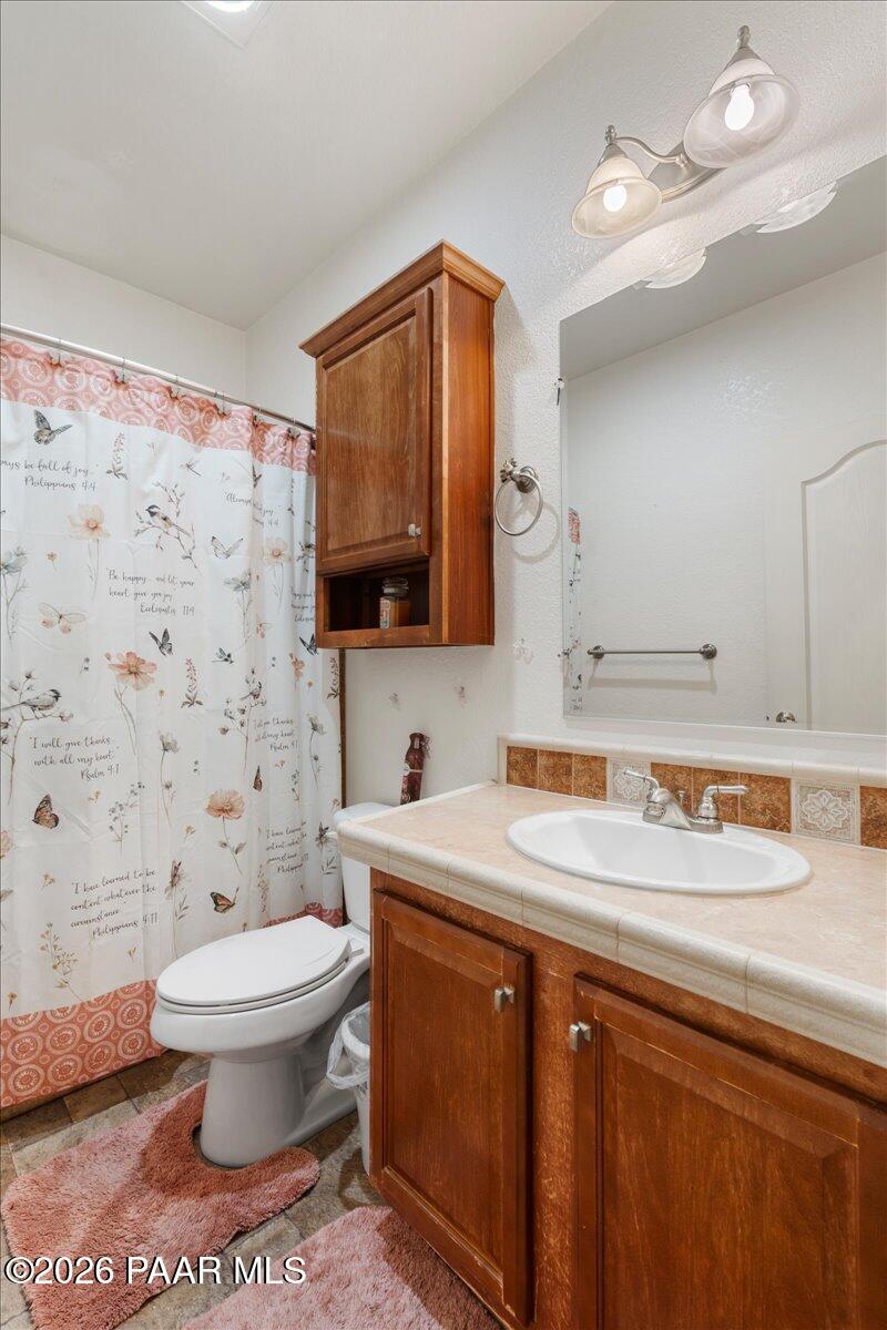 8475 West Red Rock Road Kirkland, AZ 86332 - Photo 26 of 39 a bathroom with a sink toilet a mirror and shower curtain