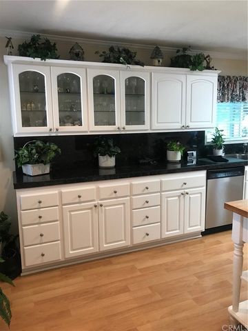 a kitchen with granite countertop a refrigerator a microwave a stove and white cabinets